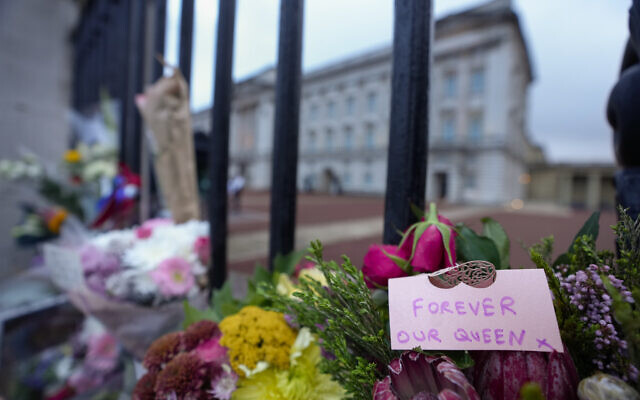 Flowers and a message are seen outside Buckingham Palace, rear, in London, Friday, Sept. 9, 2022. Queen Elizabeth II, Britain's longest-reigning monarch and a rock of stability across much of a turbulent century, died Thursday Sept. 8, 2022, after 70 years on the throne. She was 96. (AP Photo/Kirsty Wigglesworth)