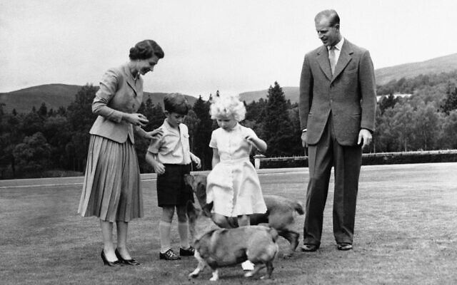 FILE - Queen Elizabeth II and the Duke of Edinburgh, with their children Prince Charles and Princess Anne, play with the Queen's corgi pet, "Sugar," foreground, and the Duke's "Candy" during the royal family's summer holiday at Balmoral castle in Scotland, on August 15, 1955. (AP Photo)