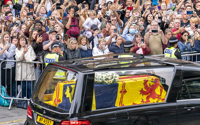 The hearse carrying the coffin of Queen Elizabeth II, draped with the Royal Standard of Scotland, passes the City Chambers on the Royal Mile, Edinburgh, September 11, 2022. (Jane Barlow/Pool Photo via AP)