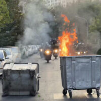 In this Sept. 20, 2022, photo taken by an individual not employed by the Associated Press and obtained by the AP outside Iran, a trash bin is burning as anti-riot police arrive during a protest over the death of a young woman who had been detained for allegedly violating the country's conservative dress code, in downtown Tehran, Iran (AP Photo)