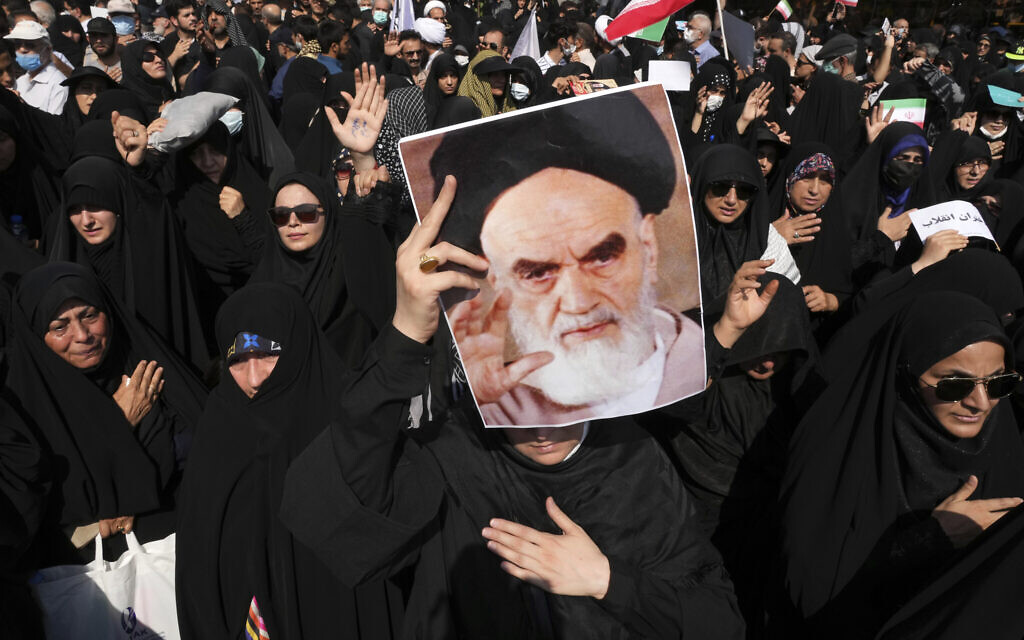A pro-government demonstrator holds a poster of the late Iranian revolutionary founder Ayatollah Khomeini while attending a rally after the Friday prayers to condemn recent anti-government protests over the death of a young woman in police custody, in Tehran, Iran, Sept. 23, 2022. (Vahid Salemi/AP)