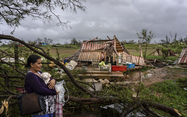 Mercedes Valdez holds her dog Kira as she waits for transportation after losing her home to Hurricane Ian in Pinar del Rio, Cuba, Sept. 27, 2022. (AP Photo/Ramon Espinosa)