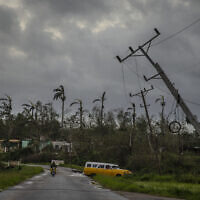 A classic American car drives past utility poles tilted by Hurricane Ian in Pinar del Rio, Cuba, Sept. 27, 2022. (AP Photo/Ramon Espinosa)