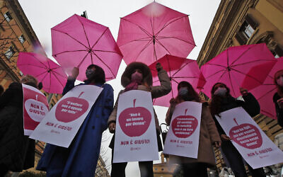 Women wear signs with writing in Italian that say "Welfare is not the same for all," left, "It's not a woman's job," second from left, "Men advance; childbirth is not their problem," and "I don't have children but to be discriminated it's enough to be a woman," right, during a demonstration in front of the Finance Ministry on International Women's Day in Rome, March 8, 2021. (AP Photo/Alessandra Tarantino, File )