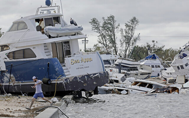 Joe Dalton, on vacation from Cleveland, Ohio, checks out beached boats at Fort Myers Wharf along the Caloosahatchee Rive, September 29, 2022, in Fort Myers, Florida., following Hurricane Ian. (Amy Beth Bennett/South Florida Sun-Sentinel via AP)