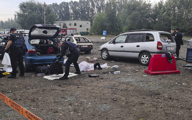 Police officers check the bags of killed civilians after a Russian rocket attack in Zaporizhzhia, Ukraine, Friday, Sept. 30, 2022. (AP Photo/Viacheslav Tverdokhlib)