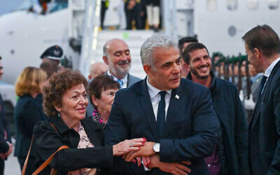 Prime Minister Yair Lapid, on a state visit to Germany, helps Holocaust survivor Shoshana Trister descend from the aircraft in Berlin after she was overcome with emotion upon seeing German soldiers, September 12, 2022. (GPO/Kobi Gideon)