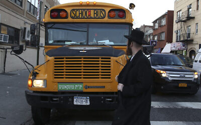 Illustrative: A man walks by school bus with Yiddish signage in Borough Park, Brooklyn, New York City, January 1, 2014. (Nati Shohat/Flash90)