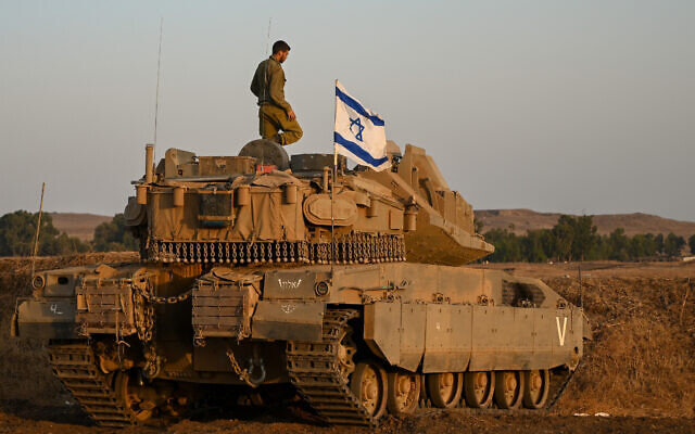 A soldier stands atop a tank ahead of a night drill in the central Golan Heights, on August 29, 2022. (Michael Giladi/Flash90)
