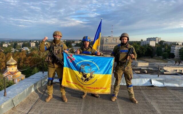 Ukrainian soldiers pose with a flag after retaking the town of Kupiansk near Kharkiv from Russian force, September 10, 2022. (Social media; used in accordance with Clause 27a of the Copyright Law)
