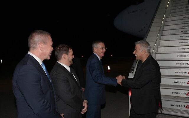 Prime Minister Yair Lapid (right) is greeted by (right to left) Ambassador to the US Michael Herzog, Consul-General in New York Asaf Zamir, and UN Ambassador Gilad Erdan, on the tarmac at JFK airport in New York on September 20, 2022. (Avi Ohayon/GPO)