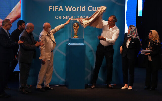 Tehran's city council chairman Mehdi Chamran, left, and former Iranian national soccer team captain Ahmad Reza Abedzadeh, right, reveal the FIFA World Cup trophy during the Trophy Tour, at Milad Tower hall in Tehran, Iran, September 1, 2022. (AP Photo/Vahid Salemi)