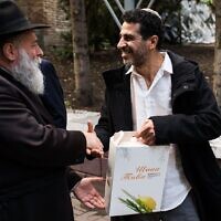Kyiv Chief Rabbi Jonathan Markovich, left, hands a Rosh Hashanah package to a member of the local Jewish community. (Courtesy)