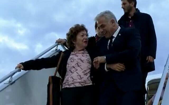Prime Minister Yair Lapid (R) helps Holocaust survivor Shoshana Trister descend from the aircraft after she was overcome with emotion on seeing German soldiers upon arriving in Berlin on September 12, 2022. (Screencapture/Channel 12)