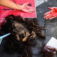 Woman pose with locks of their own hair after cutting them during a protest on October 1, 2022 in Rome, following the death of Kurdish woman Mahsa Amini in Iran (Vincenzo PINTO / AFP)