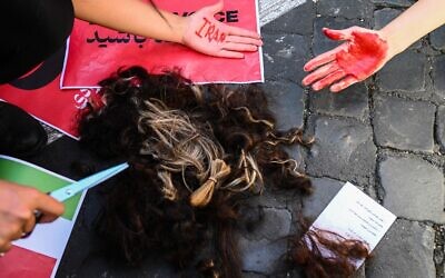 Woman pose with locks of their own hair after cutting them during a protest on October 1, 2022 in Rome, following the death of Kurdish woman Mahsa Amini in Iran (Vincenzo PINTO / AFP)