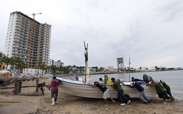 Fishermen take a boat out of the water ahead of the arrival of Hurricane Orlene, in Mazatlan, state of Sinaloa, Mexico, on October 2, 2022. (AFP)