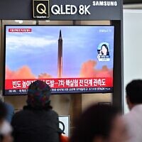 People sit near a television showing a news broadcast with file footage of a North Korean missile test, at a railway station in Seoul on October 6, 2022 (Anthony WALLACE / AFP)