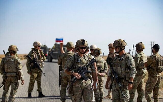 Soldiers of a Russian military convoy and their US counterparts exchange greetings as their patrol routes intersect in an oil field near Syria's al-Qahtaniyah town in the northeastern Hasakah province, close to the border with Turkey, on October 8, 2022. (Delil SOULEIMAN / AFP)