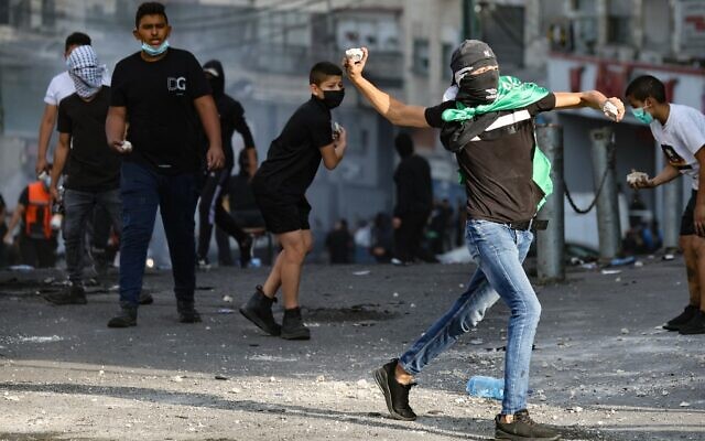 Palestinians hurl rocks at Israeli security forces during clashes in the Shuafat refugee camp in East Jerusalem, on October 12, 2022. (Ahmad Gharabli/AFP)
