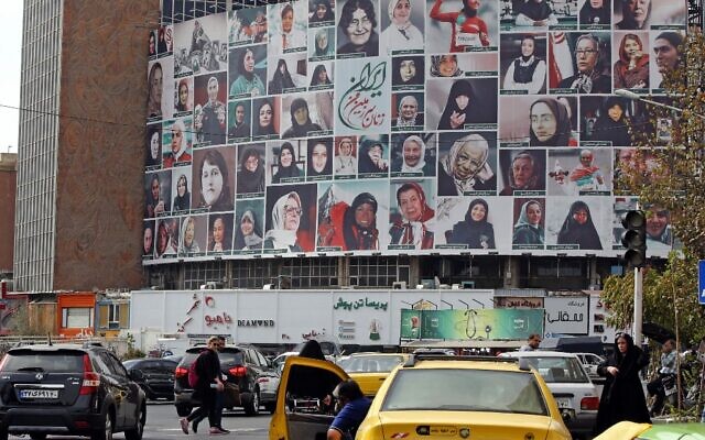 Iranians drive past a huge billboard showing a montage of pictures titled 'the women of my land, Iran' featuring Iranian women who are all observing the hijab, on Valiasr Square in Tehran, on October 13, 2022. (Photo by AFP)
