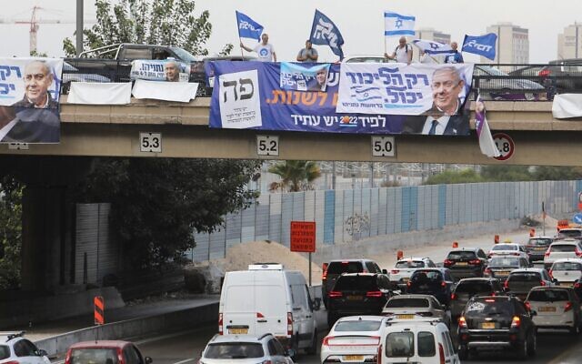Likud supporters wave party and national flags on an overpass overlooking a highway in the coastal city of Tel Aviv, on October 23, 2022. (GIL COHEN-MAGEN / AFP)