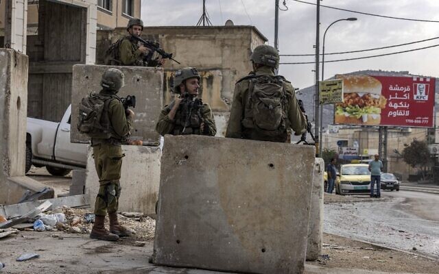 Israeli soldiers stand guard by concrete blocks in the Palestinian village of Huwara, south of Nablus in the West Bank on October 26, 2022. (Menahem Kahana / AFP)