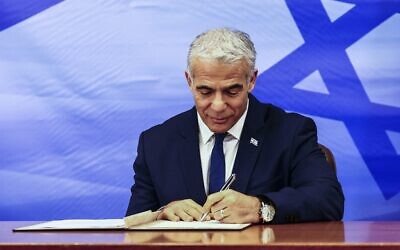 Prime Minister Yair Lapid signs the US-brokered deal setting a maritime border between Israel and Lebanon, at the Prime Minister's office in Jerusalem October 27, 2022. (RONEN ZVULUN / AFP)