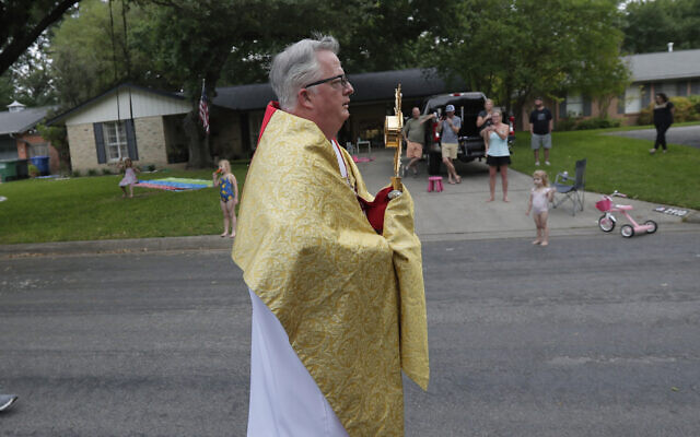 Using social distancing due to the COVID-19 pandemic, the Rev. Pat O'Brien, of St.Pius X Catholic Church, leads a Eucharistic procession through a neighborhood near his church in San Antonio, Monday, April 27, 2020. (AP/Eric Gay)