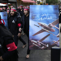 Shiite Lebanese members of Iranian-backed Hezbollah walk barefoot as they carry a poster showing Hezbollah drones with Arabic words that reads: "We are coming," during the holy day of Ashoura in a southern suburb of Beirut, Lebanon, Tuesday, Aug. 9, 2022. (AP/Hussein Malla)
