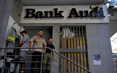 A man, left, uses an ATM to withdraw money, as security stand guard outside A Bank Audi branch, in Beirut, Lebanon, Monday, September 26, 2022. (AP/Bilal Hussein)