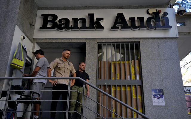 A man, left, uses an ATM to withdraw money, as security stand guard outside A Bank Audi branch, in Beirut, Lebanon, Monday, September 26, 2022. (AP/Bilal Hussein)