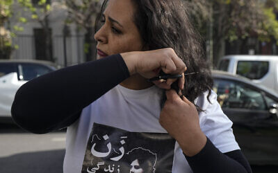An Iranian woman cuts a lock of her hair during a rally against the death of Iranian Mahsa Amini, in front of the Chilean Human Rights Institute building in Santiago, Chile, Sept. 30, 2022 (AP Photo/Esteban Felix)