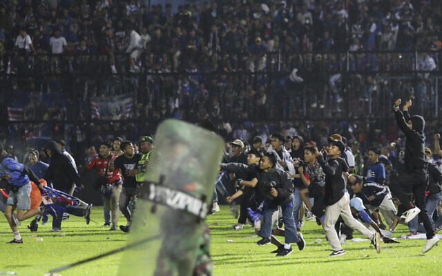 Soccer fans enter the pitch during a clash between supporters at Kanjuruhan Stadium in Malang, East Java, Indonesia, Saturday, Oct. 1, 2022. Panic following police actions left over 100 dead, mostly trampled to death, police said Sunday. (AP/Yudha Prabowo)