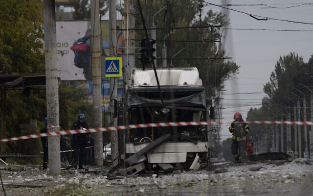 Firefighters and police officers work on a site where an explosion damaged a bus after a Russian attack in Dnipro, Ukraine, Monday, Oct. 10, 2022. (AP Photo/Leo Correa)