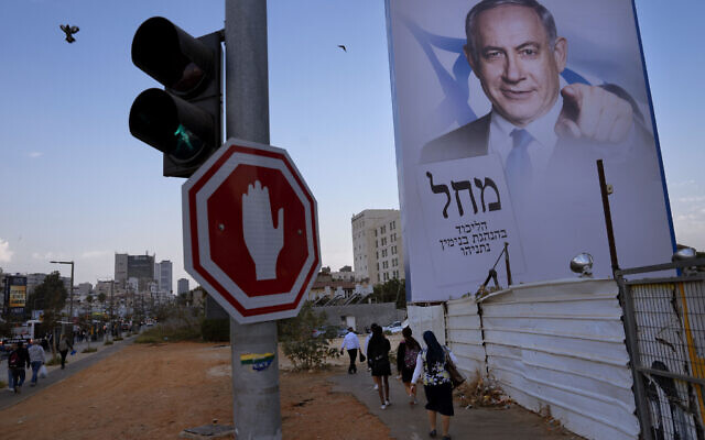 People walk past an election campaign billboard showing Benjamin Netanyahu, former Prime Minister and the head of Likud party, in Bnei Brak, Israel, Tuesday, October 25, 2022. Israel is heading into its fifth election in under four years on November 1. (AP Photo/Oded Balilty)