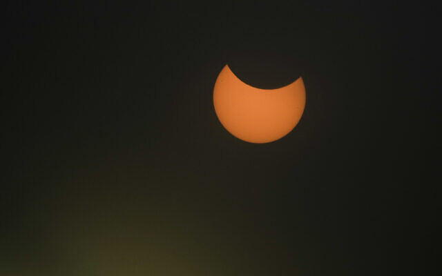 Through a filter this partial solar eclipse, the moon covers a part of the sun in the town of Givatayim, near Tel Aviv, October 25, 2022. (AP Photo/Ariel Schalit)