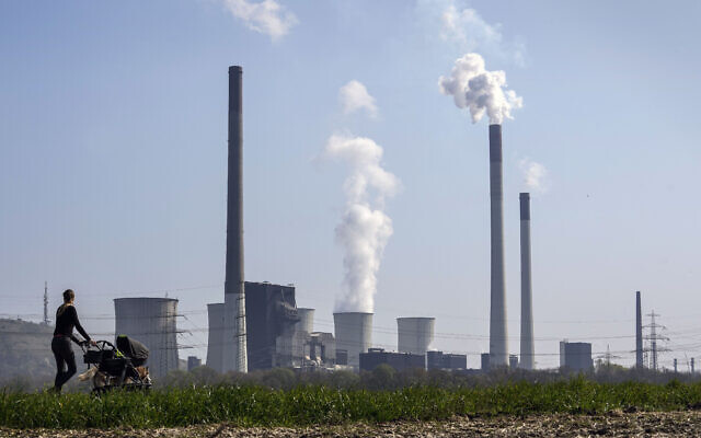 A mother pushes a stroller in front of the Scholven coal-fired power station, owned by Uniper, in Gelsenkirchen, Germany, March 28, 2022 (AP Photo/Martin Meissner, File)
