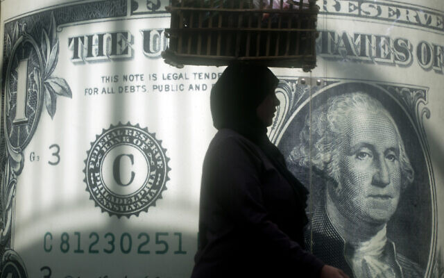 FILE - An Egyptian vendor walks past a poster showing a U.S. dollar outside an exchange office in Cairo, Egypt, Wednesday, Nov. 9, 2016.  (AP Photo/Amr Nabil, File)