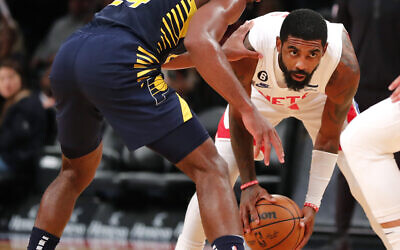 Brooklyn Nets guard Kyrie Irving looks for help against Indiana Pacers guard Buddy Hield during the second half of an NBA basketball game, Oct. 29, 2022, in New York. (AP Photo/Noah K. Murray)