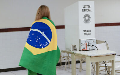 A voter wrapped in a Brazilian flag arrives to vote in a presidential a run-off pitting President Jair Bolsonaro against former president Luiz Inácio Lula da Silva, in Brasilia, Brazil, Oct. 30, 2022. (AP Photo/Eraldo Peres)
