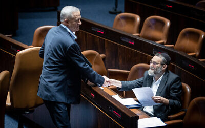 Benny Gantz, left, shakes hands with UTJ MK Moshe Gafni at the Knesset in Jerusalem, on August 15, 2022. (Oren Ben Hakoon/Flash90)