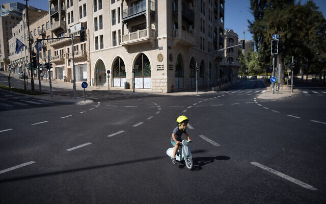 People ride their bicycles and walk along the empty road in Jerusalem, on Yom Kippur, the Day of Atonement, and the holiest of Jewish holidays, October 4, 2022. (Yonatan Sindel/Flash90)