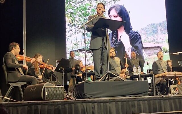 Iranian singer Homayoun Shajarian performs on stage in Melbourne, Australia, against a background image of Mahsa Amini, on September 23, 2022. (Screenshot used in accordance with Clause 27a of the Copyright Law)