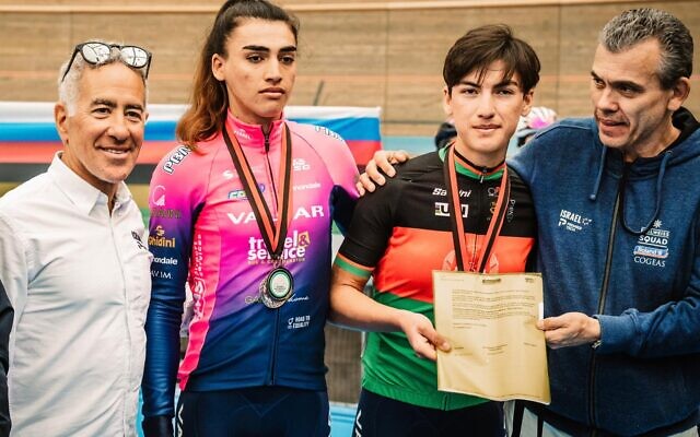 Afghanistan's national cycling champion Fariba Hashimi (2R) and her sister Yulduz (2L) receive their contracts from the owner of Women’s WorldTour team Israel – Premier Tech Roland, Sylvan Adams, in Aigle, Switzerland, October 23, 2022. (Noa Arnon/courtesy)