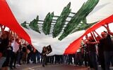 Supporters of Lebanon's President Michel Aoun cheer under a large national flag, as he prepares to leave the presidential palace in Babbda at the end of his mandate, east of the capital Beirut, on October 30, 2022. (Anwar Amro / AFP)
