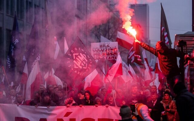 Participants burn flares and wave a Polish flag as they take part in Poland's Independence Day march organized by nationalist groups in Warsaw on November 11, 2022. (Wojtek Radwanski/AFP)