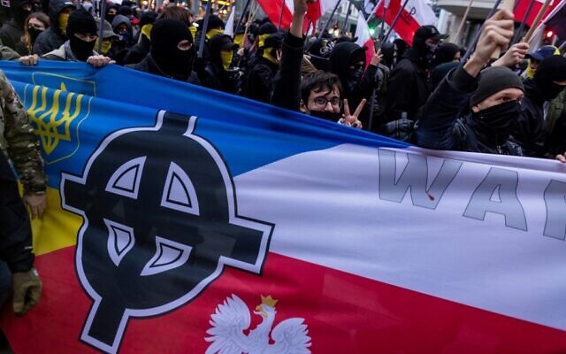 A Celtic Cross is seen on a banner with the Polish and Ukrainian national colors, as participants attend Poland's Independence Day march organized by nationalist groups in Warsaw on November 11, 2022. (Wojtek Radwanski/AFP)