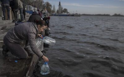 A woman takes water from the Dnipro River to use it for cleaning, in Kherson, November 14, 2022, amid Russia's invasion of Ukraine. (Photo by BULENT KILIC / AFP)