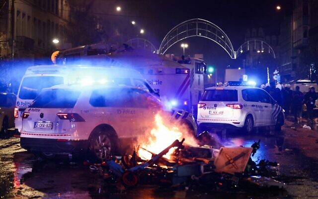 Police cars drive past burning electric scooters on the sideline of the live broadcast of the Qatar 2022 World Cup Group F football match between Belgium and Morocco, in Brussels, on November 27, 2022. (Kenzo TRIBOUILLARD / AFP)